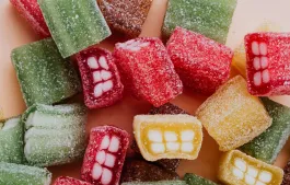 Set of colorful sour gummy sweets in sprinkle assorted chaotically on beige surface